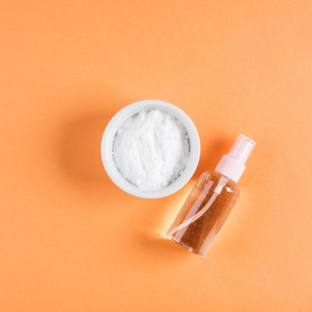 Baking soda in bowl on orange background. Concept of baking soda as multi use cleaning or beauty ingredient